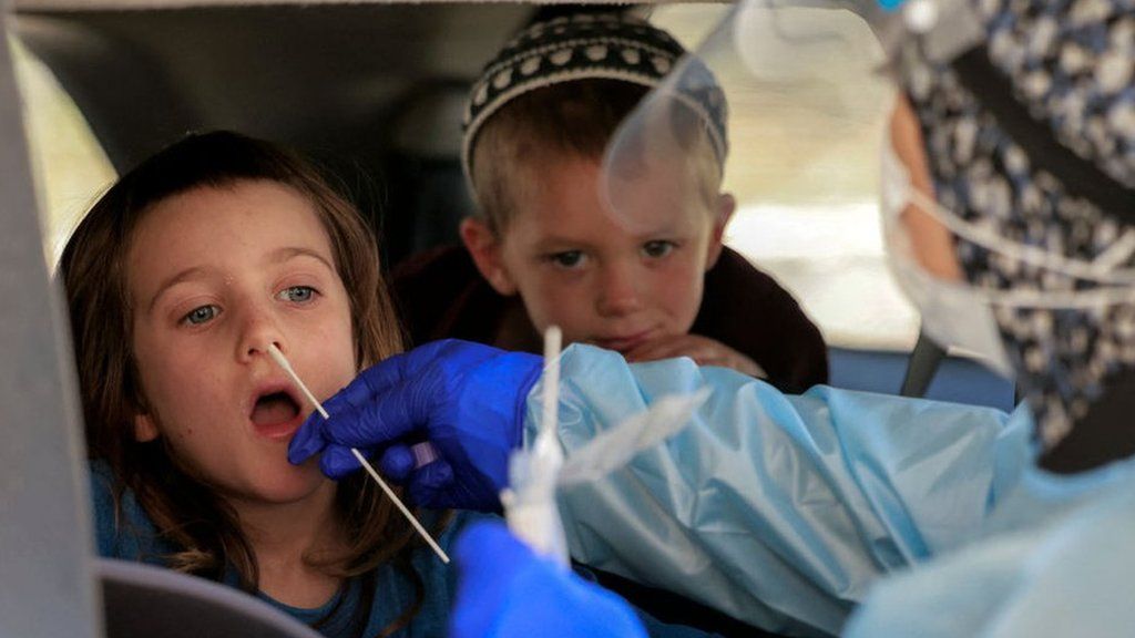File photo showing an Israeli medic performs a Covid-19 swab test on a child in a vehicle at a drive-through centre in Jerusalem on 29 July 2021