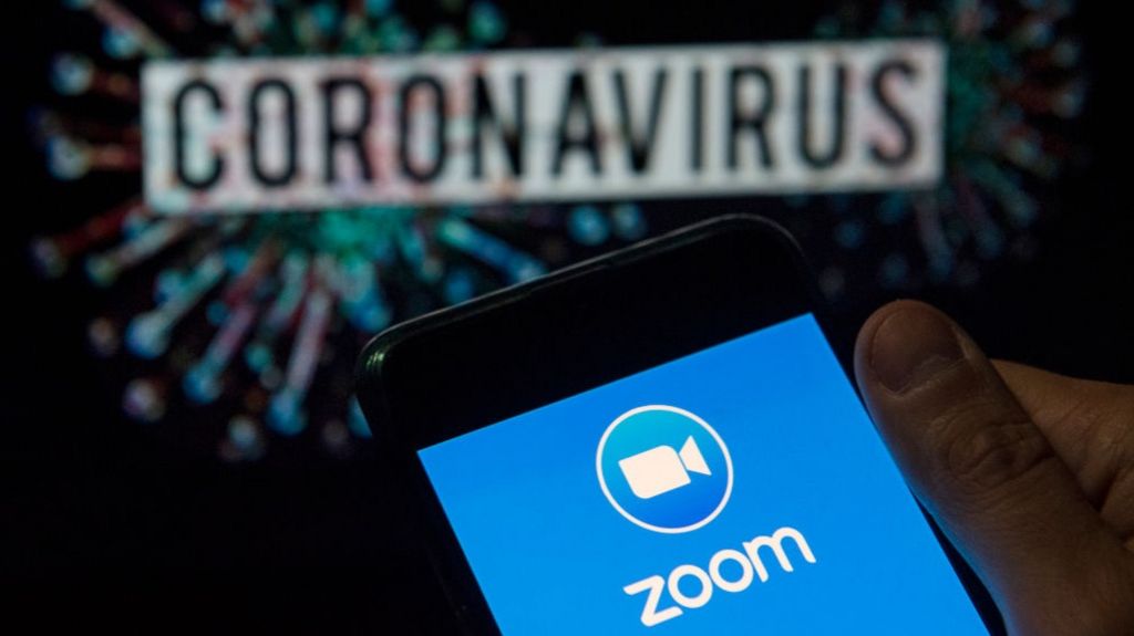 Zoom logo seen displayed on a smartphone with a computer model of the COVID-19 coronavirus on the background.