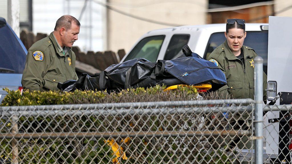 A body bag being removed from the home