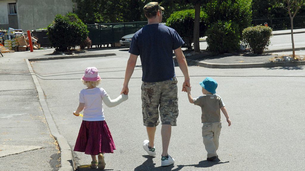 Father walks with two children into the distance