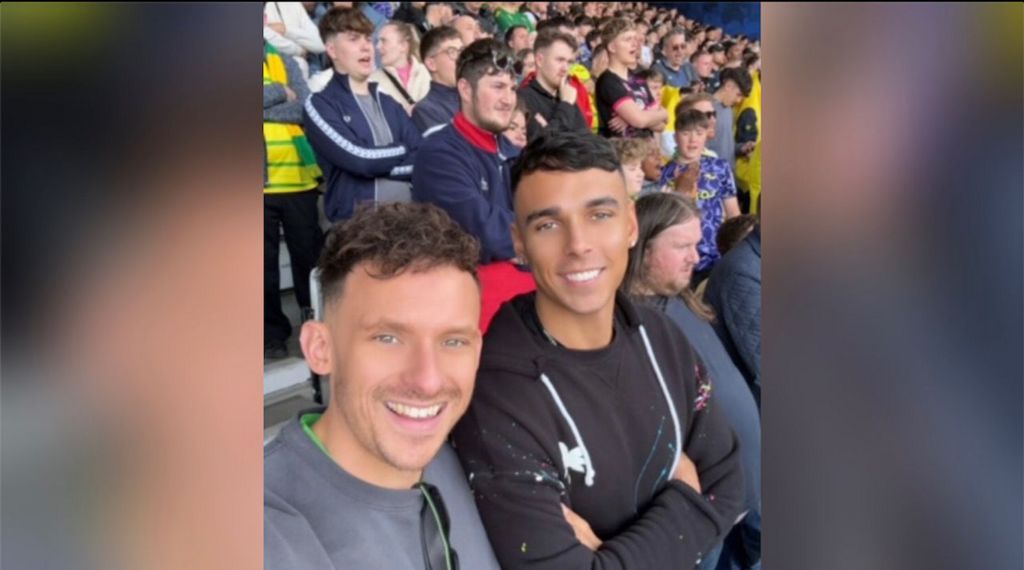 Tim Merchant with friend smiling in a football stadium