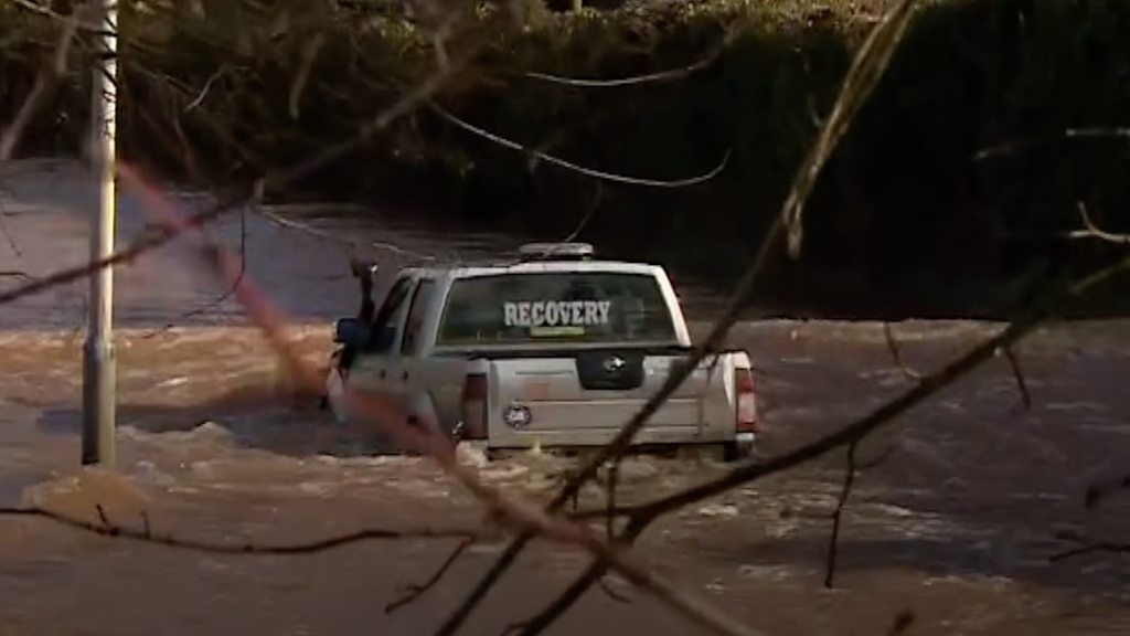 4 x 4 truck with 'recovery' markings in rear windscreen floats on flooded road