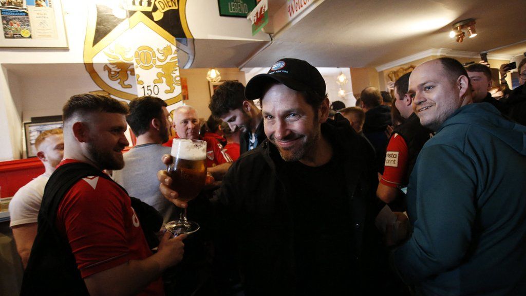 Paul Rudd holding a pint and smiling in the pub