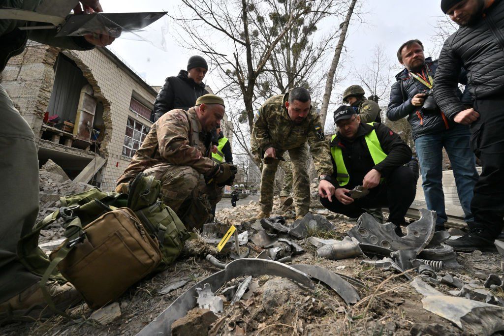 Ukrainian law enforcement officers examine fragments of a rocket at the site of a missile attack in Kyiv on March 25, 2024