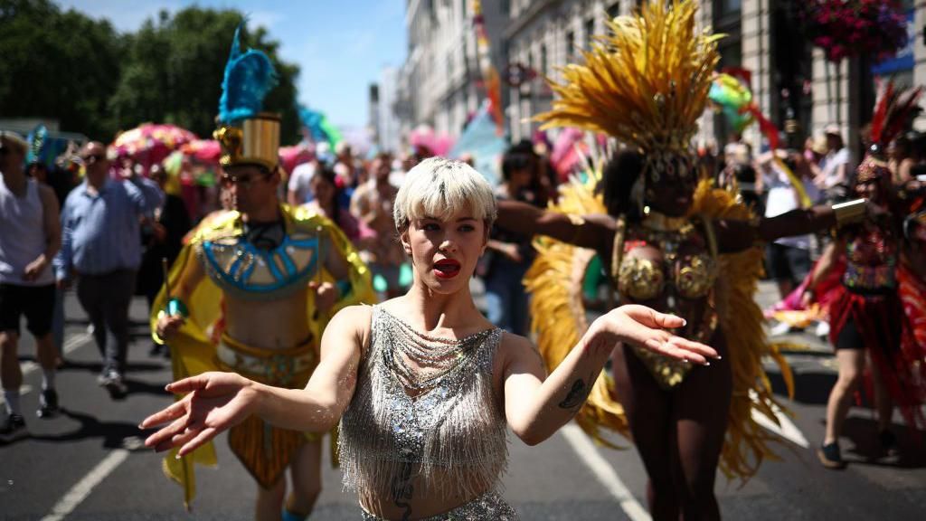 A dancer in a silver tasseled costume takes part in the parade