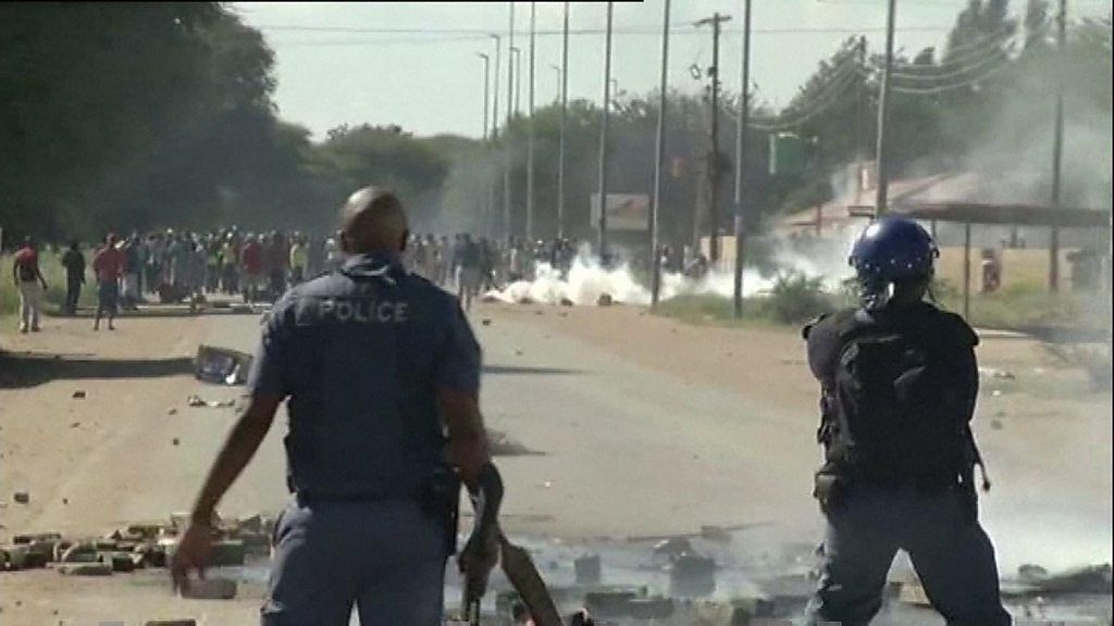 Armed police stand at protests in South Africa's North West province on 20 April