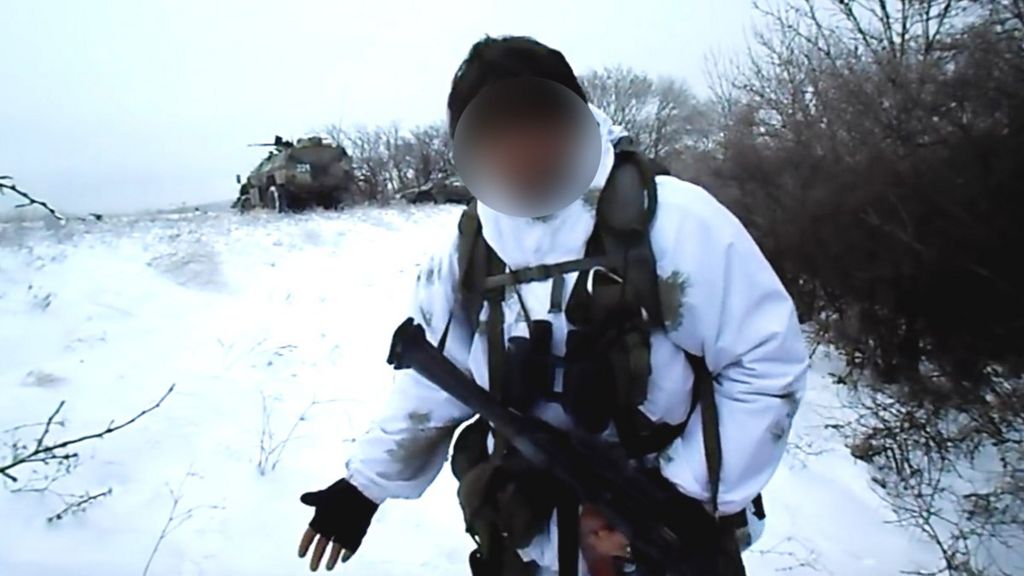 A Wagner member in the Donbas region in 2014/15 on snowy field with armoured car in background.
