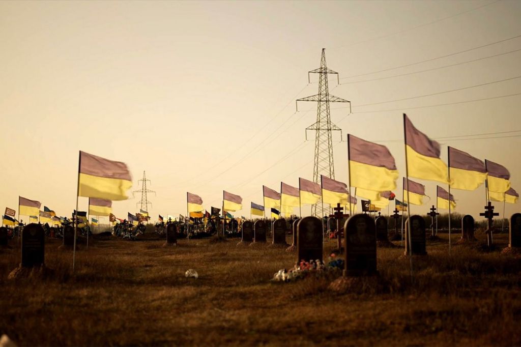 Ukrainian flags fly across a cemetery