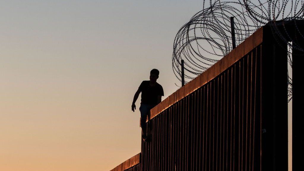 A man sits on the fence on the US-Mexico border