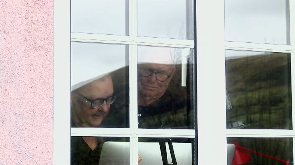 Sue Lane and her partner at their window, in self-isolation