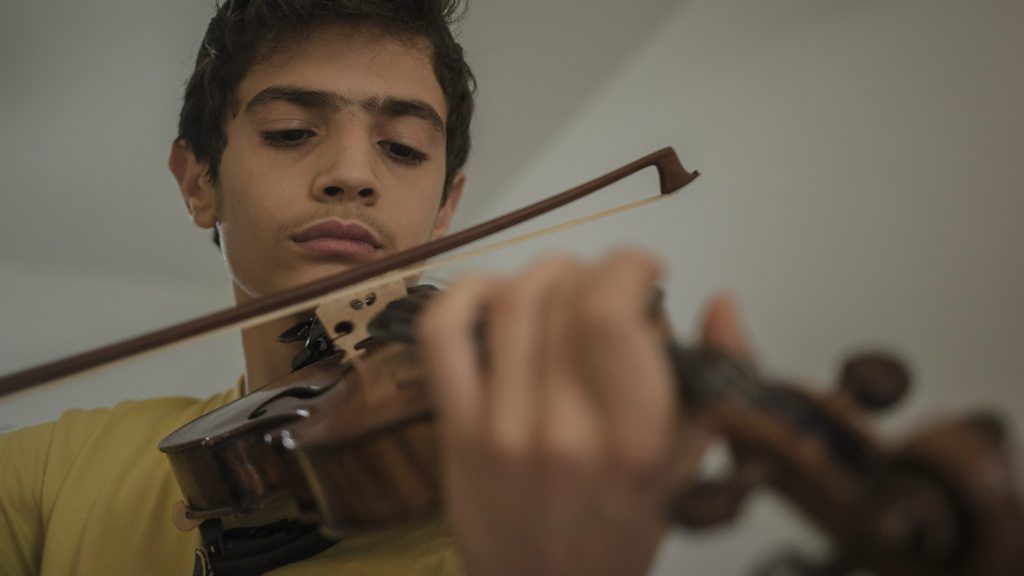 Aboud Kaplo, 14, playing the 19th century violin he was lent
