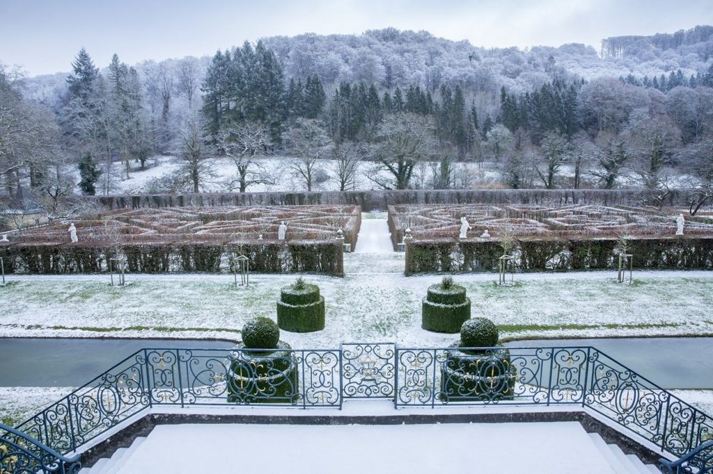 A snow-covered landscape showing a garden maze in front of a forest
