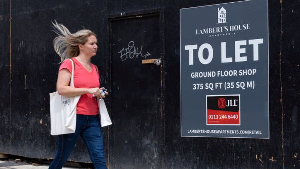 Woman beside a To Let sign on a street