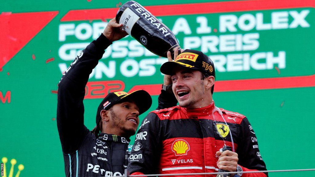 Lewis Hamilton pours champagne over Charles Leclerc on the podium at the Austrian Grand Prix in 2022
