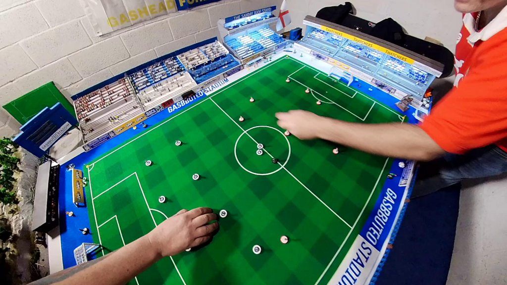 Two people play subbuteo