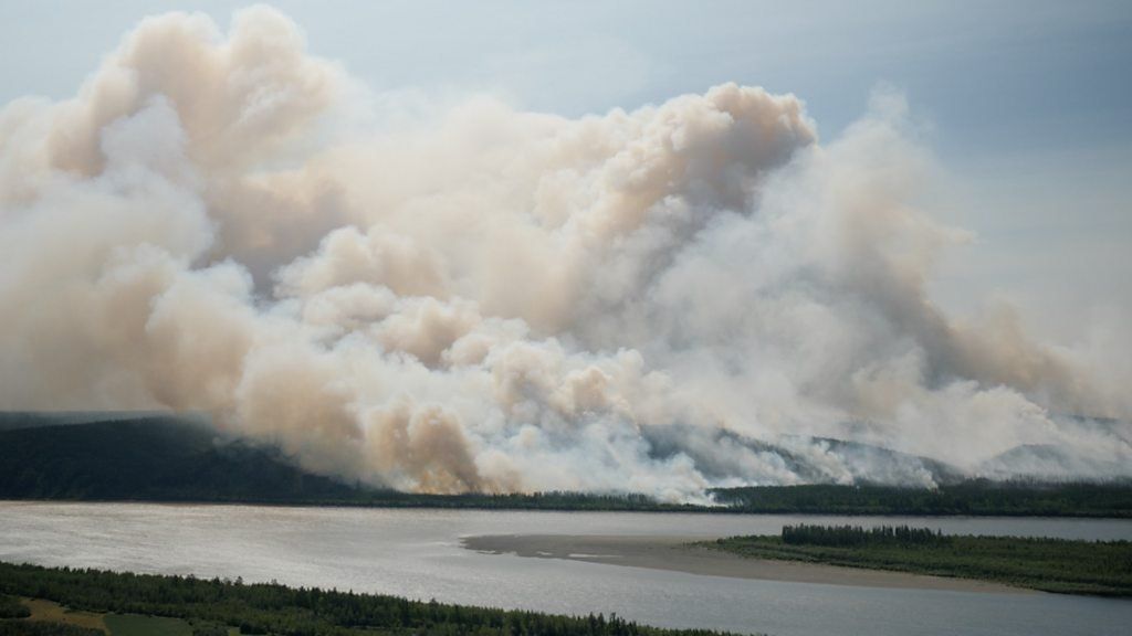 Smoke from a fire drifts over a river in Siberia