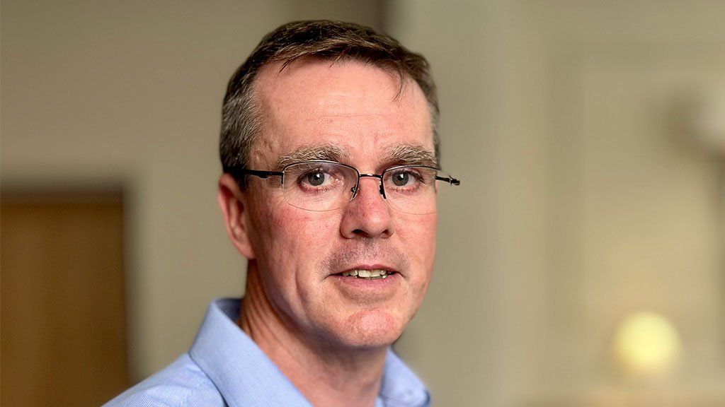 Portrait of Dr Stephen Brearey, wearing glasses and a bluish  shirt, looking straight  astatine  the camera