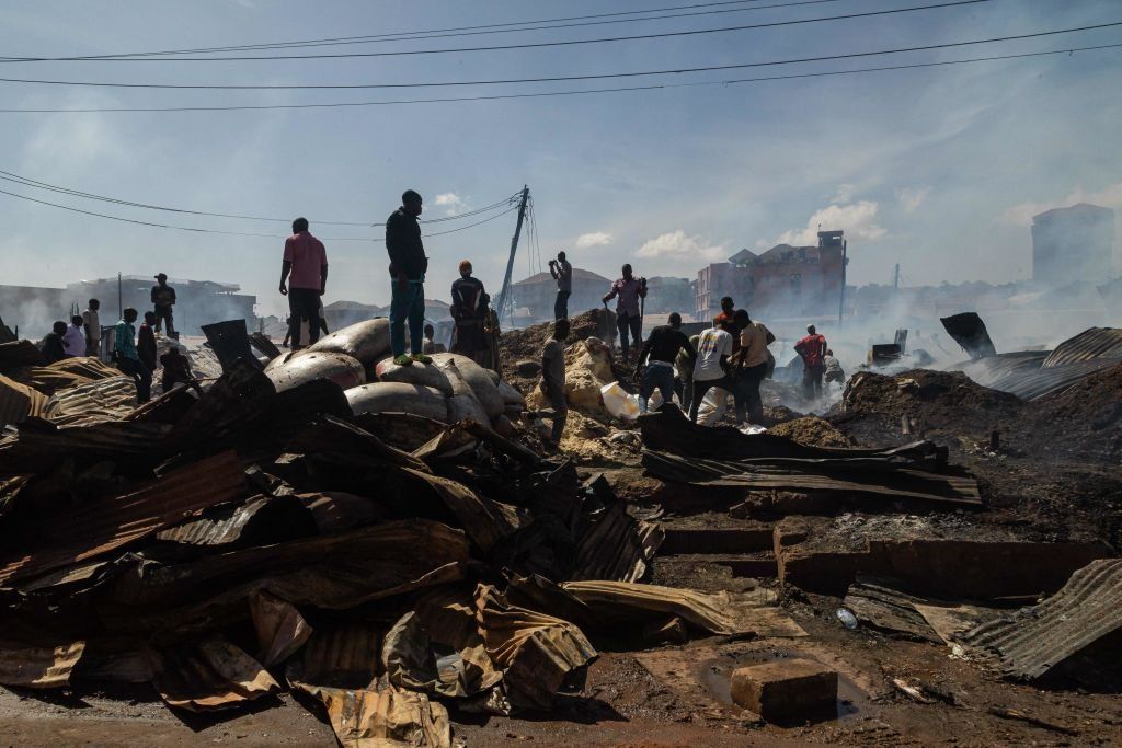 Men search through burnt matter in Kisenyi, Kampala, on February 13, 2023, following the outbreak of a fire which destroyed property and milling machines, as well as sacks of stored maize flour, millet, sorghum, and other food stuff.