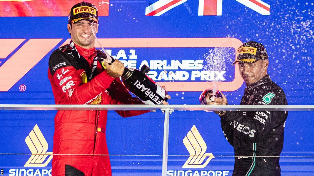Carlos Sainz celebrates winning the Singapore Grand Prix in 2023 with Lewis Hamilton on the podium