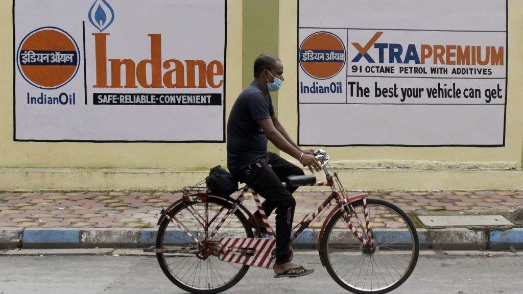 Man on a bicycle passes by a petrol station in Kolkata as oil prices rise