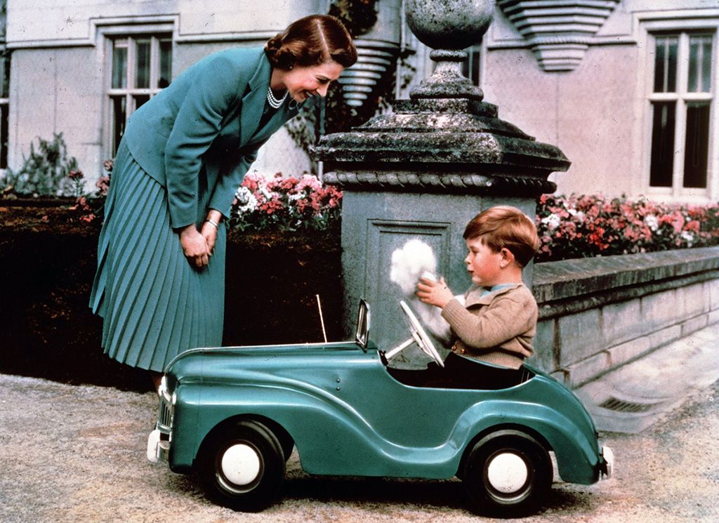 Queen Elizabeth watches Prince Charles playing in his toy car while at Balmoral, September 1952