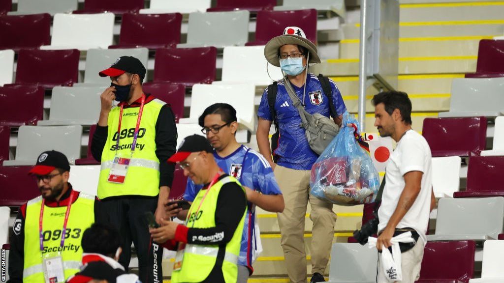 Japan fans holding bags full of rubbish with security