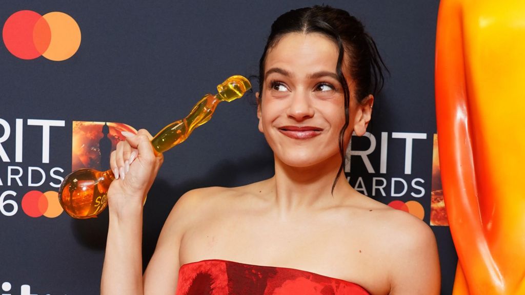 Rosalia holding up her Brit Award statuette and smiling after the ceremony