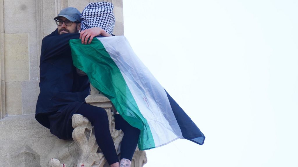 A man with a Palestine flag holding on to Elizabeth Tower.