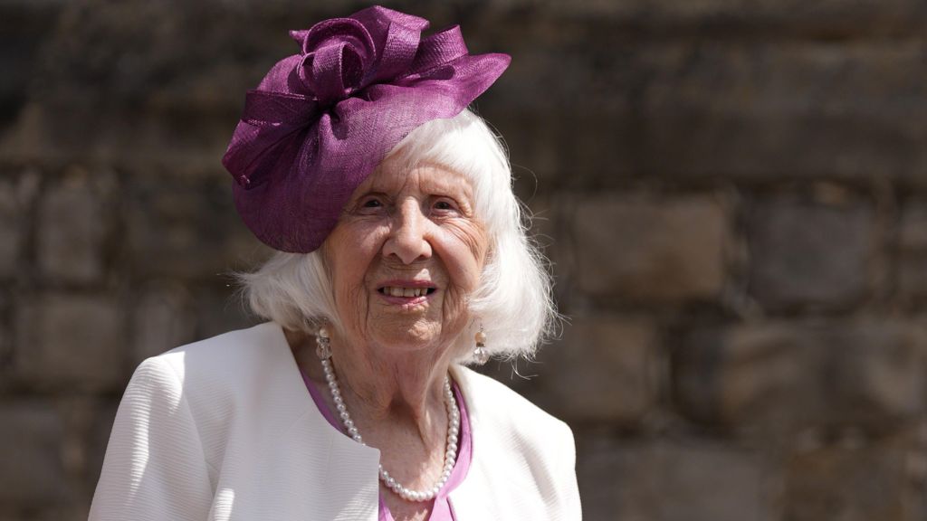 Betty Brown is staring into the camera and smiling. She has a purple flower headband on her head.