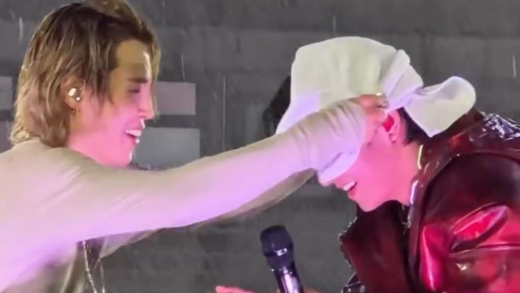 Jimin rubs a towel on V's head as BTS perform in the rain