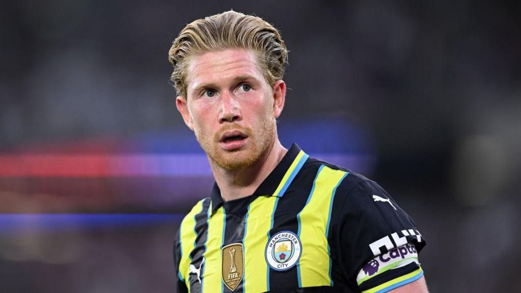 Kevin de Bruyne ក្នុង​អាវ​ក្រៅ​របស់ Manchester City ពណ៌​ខៀវ មេឃ​ខៀវ និង​លឿង