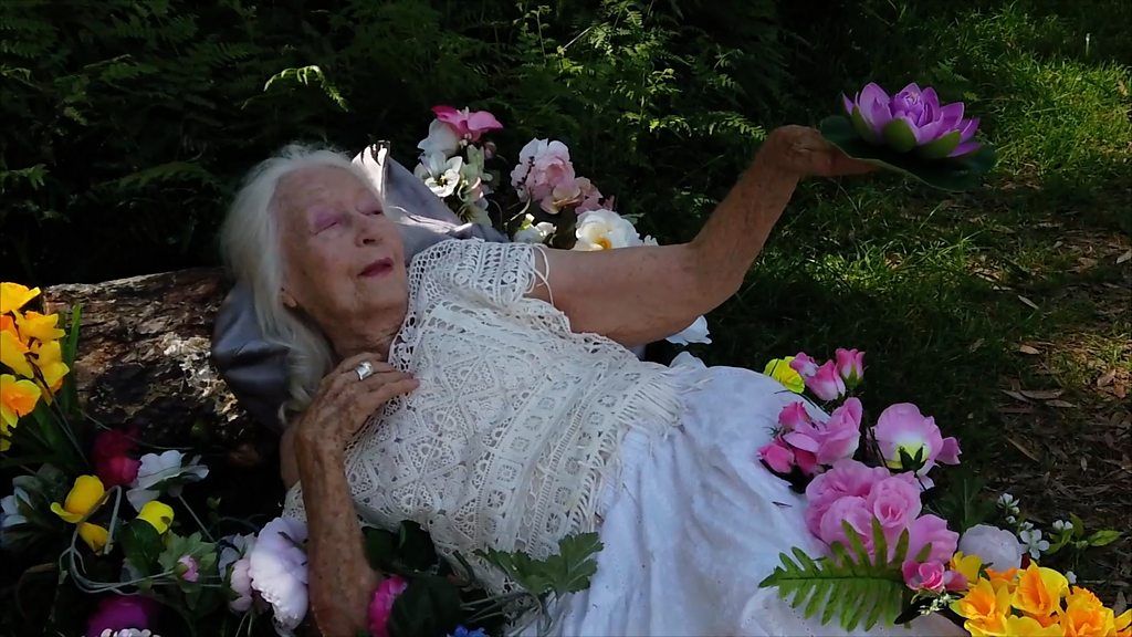 Woman lies on the ground surrounded by flowers
