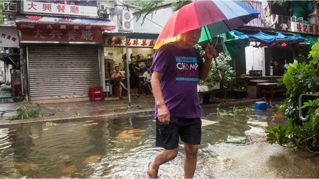 A man shields himself from heavy rain and winds brought on by Typhoon Hato.