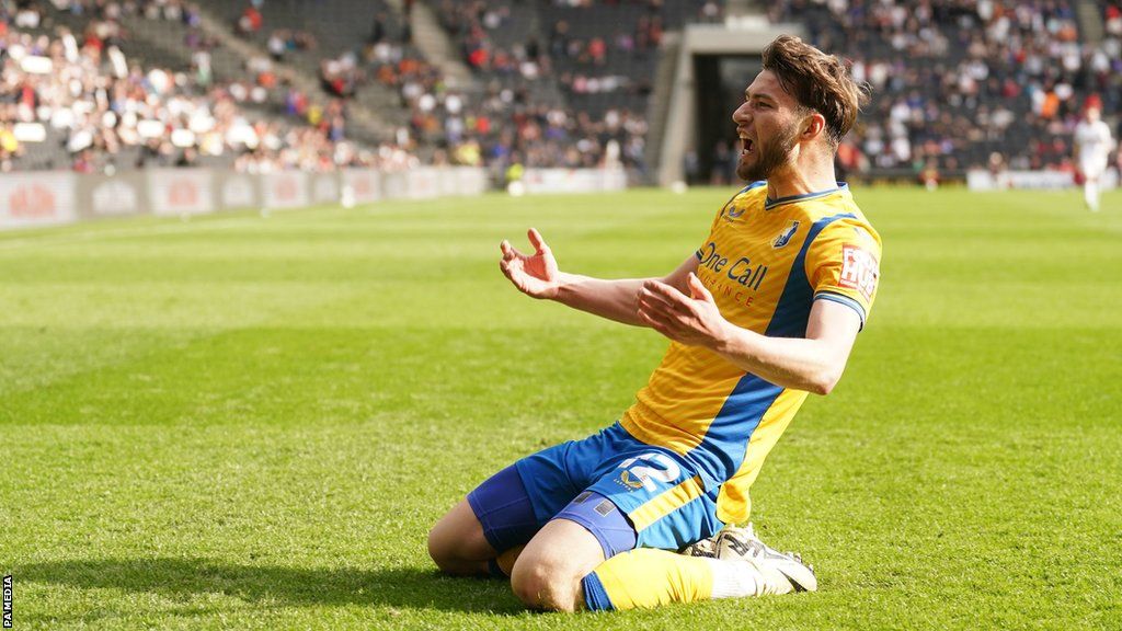 James Gale slides on his knees after scorning a goal for Mansfield at MK Dons