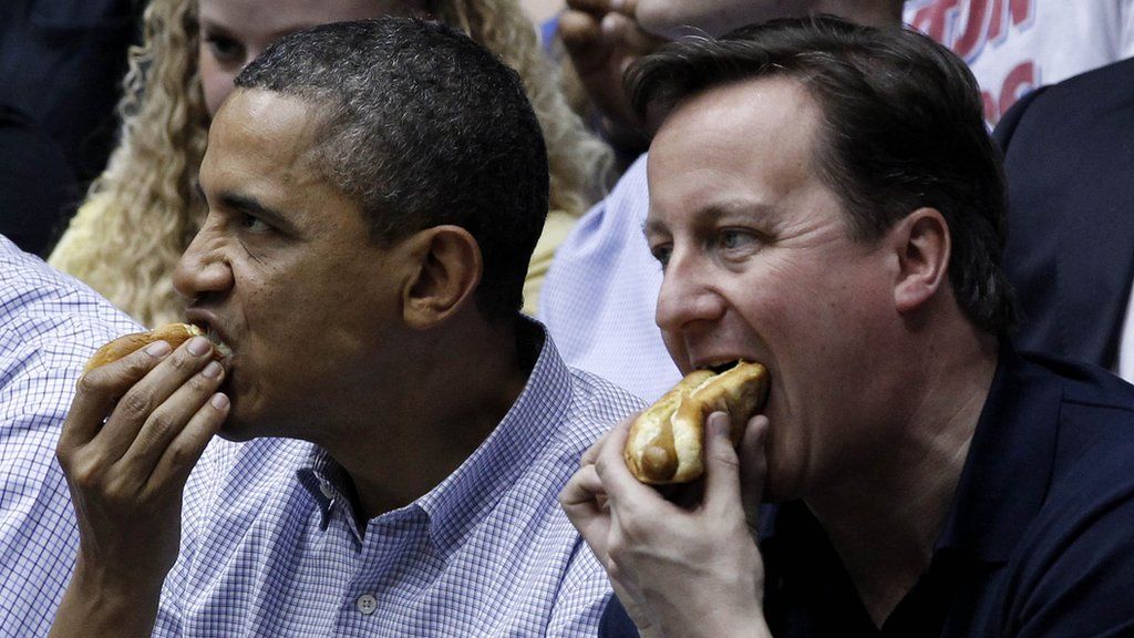 Obama and Cameron eating hot dogs at a basketball game