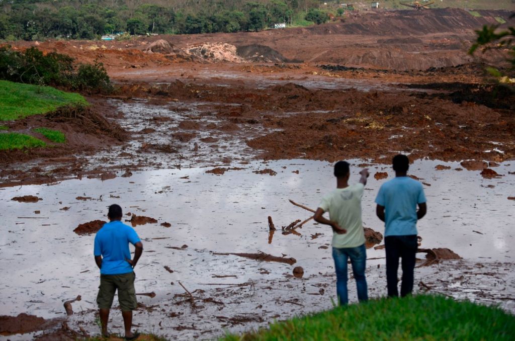 People survey the damage after the dam burst in Brazil