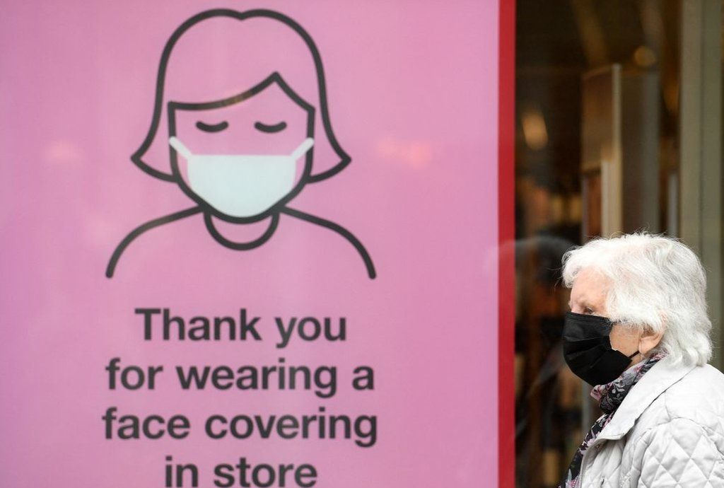 Woman walking past a mask sign