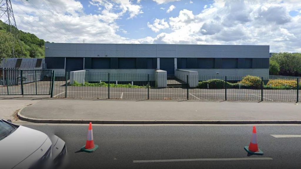 A large grey warehouse and empty car park