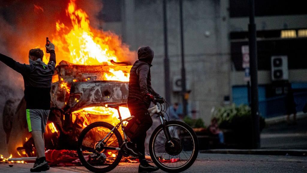 A police car is set on fire as Far-right activists hold an 'Enough is Enough' protest on 2 August, 2024 in Sunderland, England.