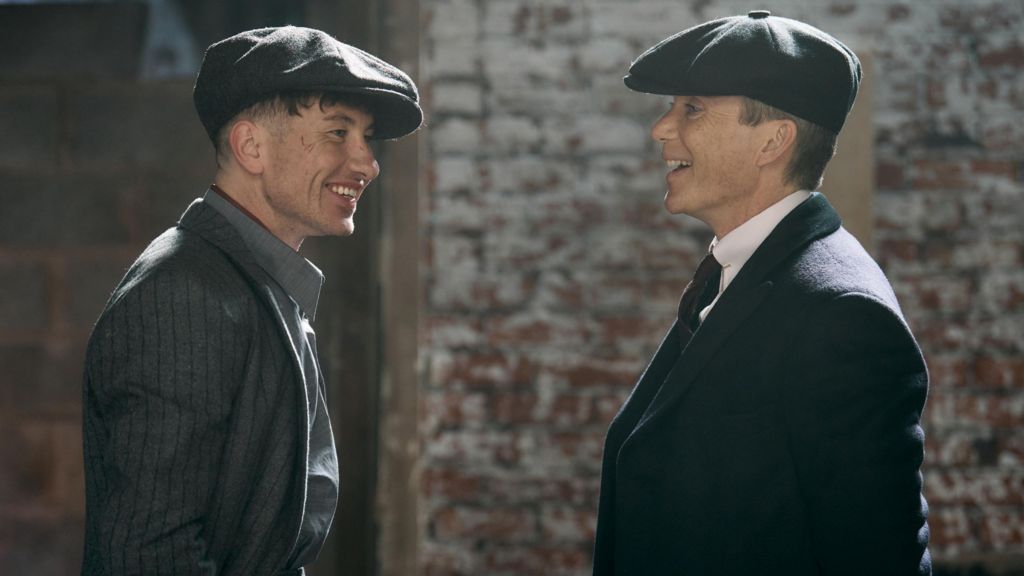 Barry Keoghan (left) and Cillian Murphy in grey suits and flat caps in a scene from the film