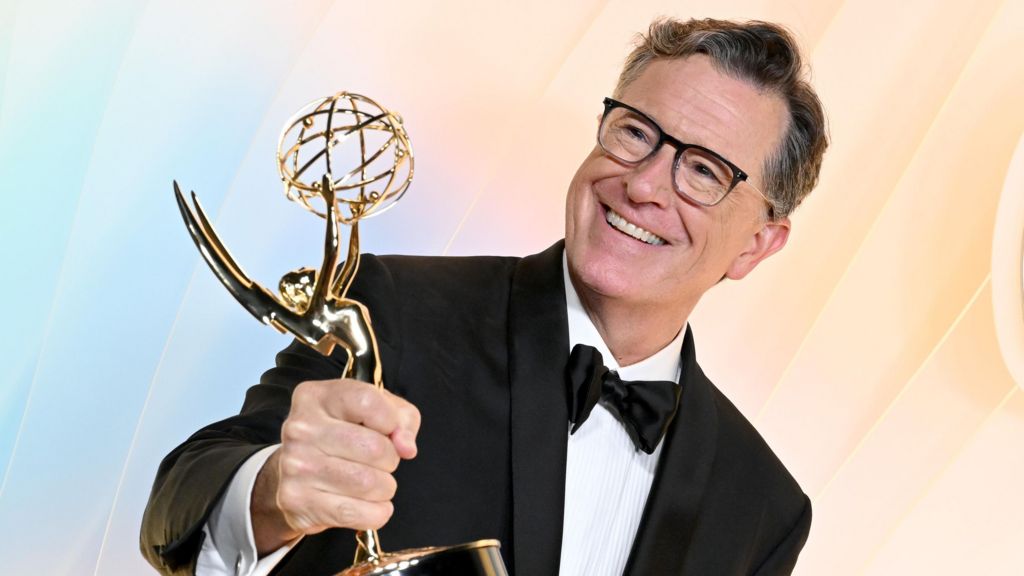 Stephen Colbert holding up his Emmy on his way in to an Emmys after party on Sunday