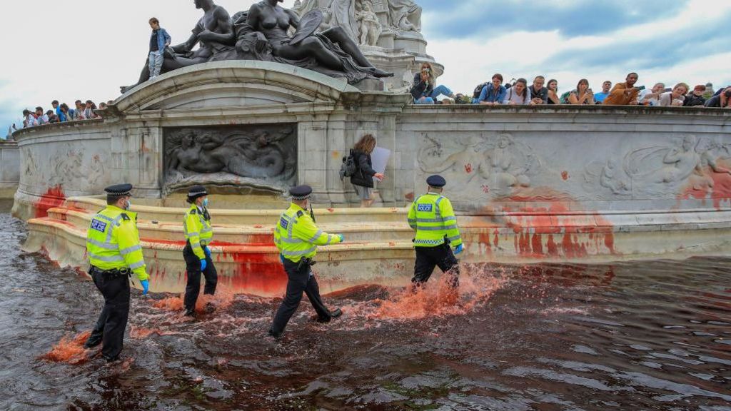 Police officers try to remove an Animal Rebellion protester in the Victoria fountain