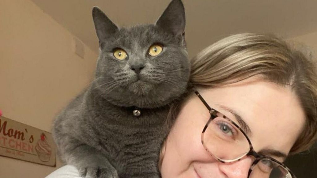 Blonde woman with grey cat on her shoulder 