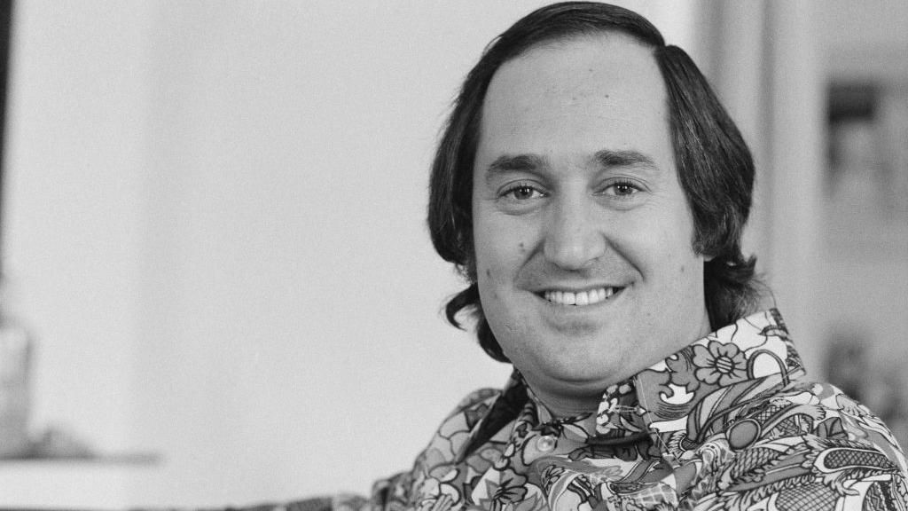 Neil Sedaka in a black and white photo wearing a 1970s style shirt