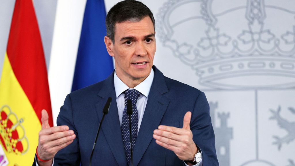 Pedro Sanchez gesturing with handsand short greying brown hair, wears a suit and tie as he speaks during a press conference