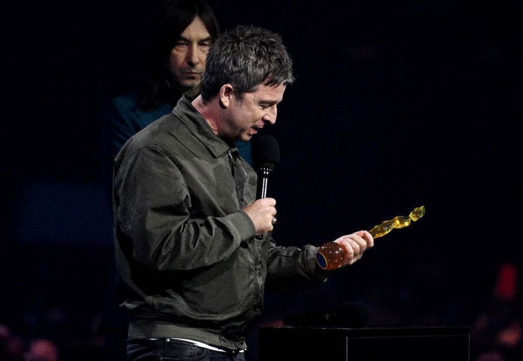 Noel Gallagher dressed in black looks at his award.