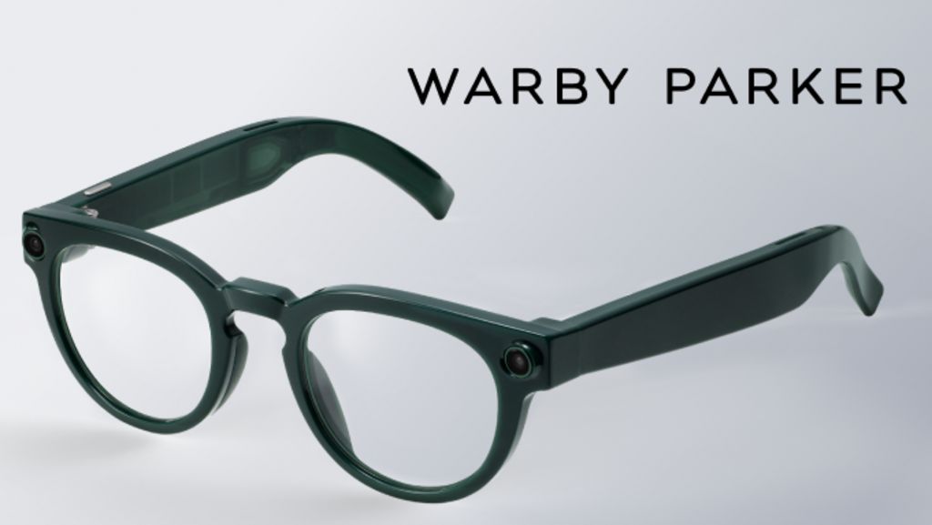 An image of Google's new smart glasses. They are slightly rounded frames in a dark green colour with small camera lenses in the corner of the frames on both sides.