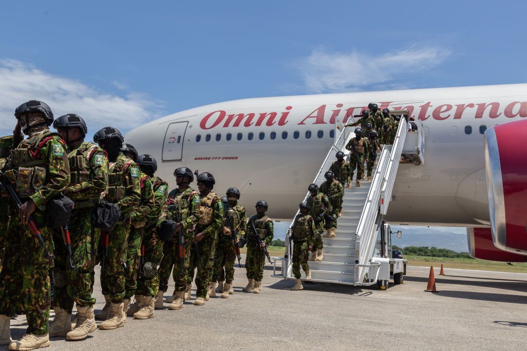 Kenyan police officers line up and march off a plane.