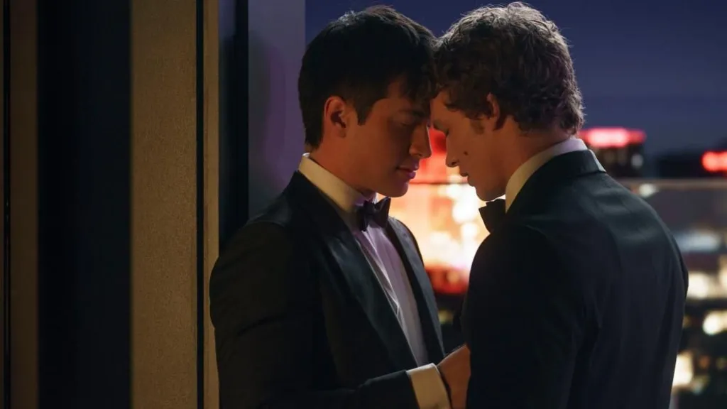 Shane Hollander, played by Hudson Williams, and Ilya Rozanov, played by Connor Storrie, both wearing tuxedos, embrace on a rooftop in a scene from Heated Rivalry.
