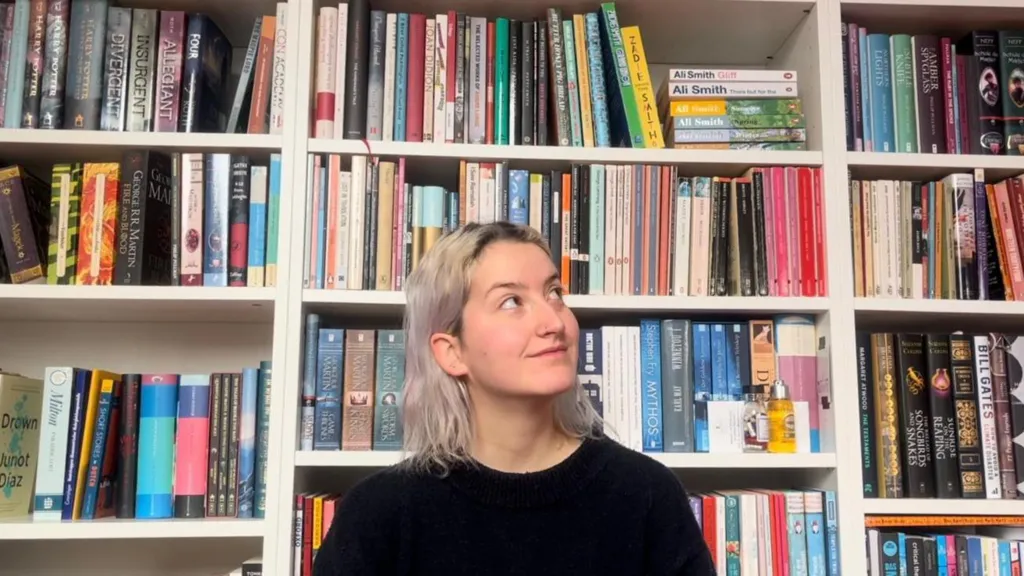 A woman with platinum blonde hair in front of books